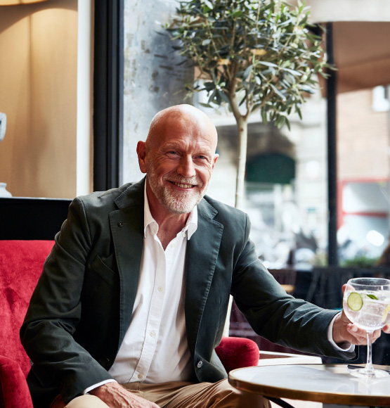 man holding a drink while siting in a red chair