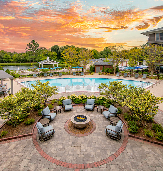 Outdoor lounge at our apartments for rent in Germantown, TN, featuring outdoor chairs, a firepit and view of the pool.